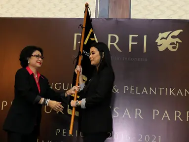 Ketua Dewan Pendiri, Debby Chintya Dewi memberikan bendera PARFI 56 kepada Ketua Umum Parfi 56, Marcella Zalianti pada acara pengukuhan dan pelantikan pengurus besar PARFI 56, Jakarta, Senin (24/10). (Liputan6.com/Herman Zakharia)