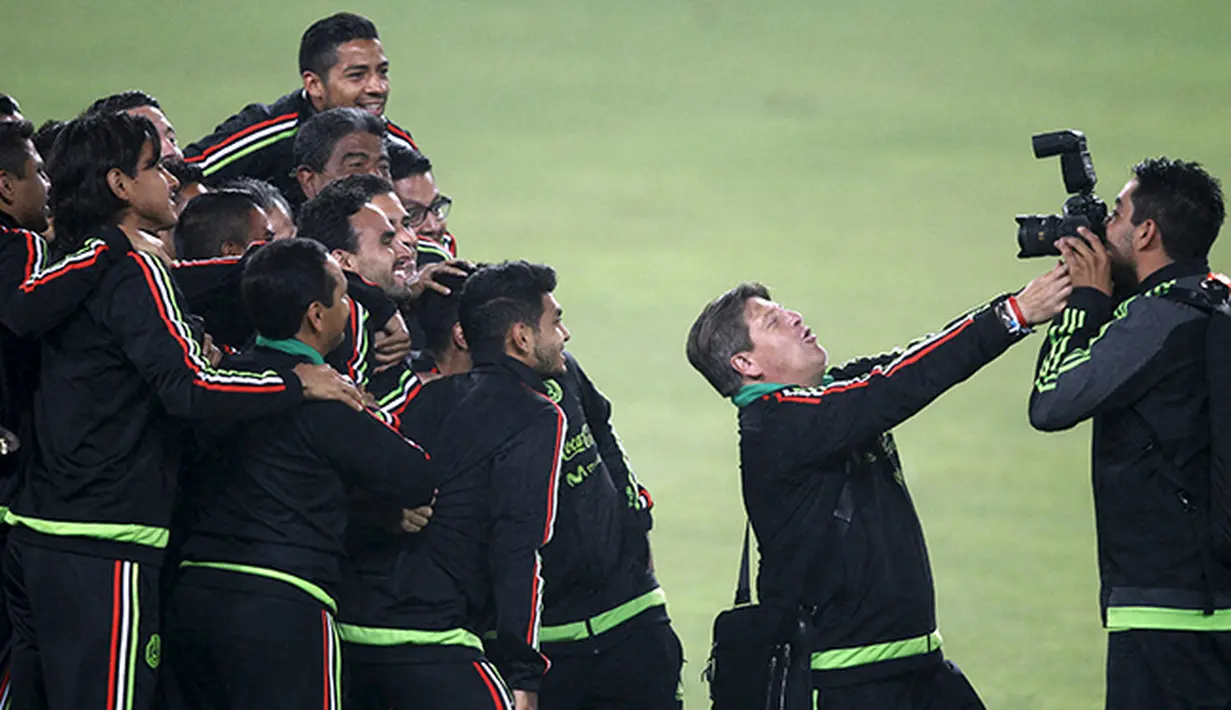 Miguel Herrera, pelatim sepak bola timnas Meksiko (kedua dari kanan) meminjam kamera fotografer untuk ber-selfie ria bersama anak asuhnya. (Reuters/Mariana Bazo)