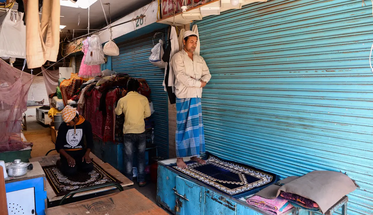 Umat Muslim melaksanakan salat di depan toko-toko yang tutup di sebuah pasar selama bulan Ramadan saat penerapan lockdown di New Delhi, Senin (4/5/2020). Di emperan toko-toko yang tutup, umat muslim salat berjemaah dengan menjaga jarak dan lainnya membaca kitab suci Alquran. (Sajjad HUSSAIN/AFP)