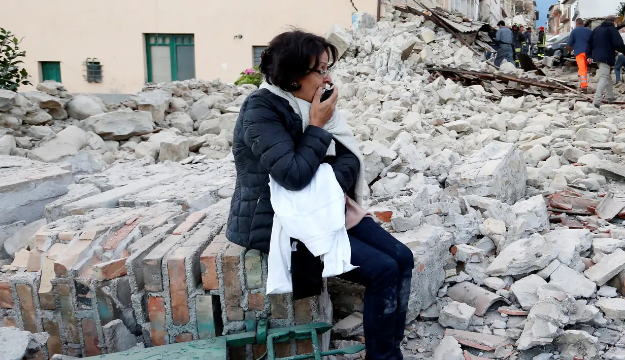 Seorang wanita duduk di antara puing bangunan yang rusak setelah gempa 6,2 SR di Amatrice, Italia tengah, Kamis (24/8). Gempa pada dini hari itu menyebabkan kerusakan besar dan getarannya membuat panik penduduk yang sedang tertidur. (REUTERS/Remo Casilli)