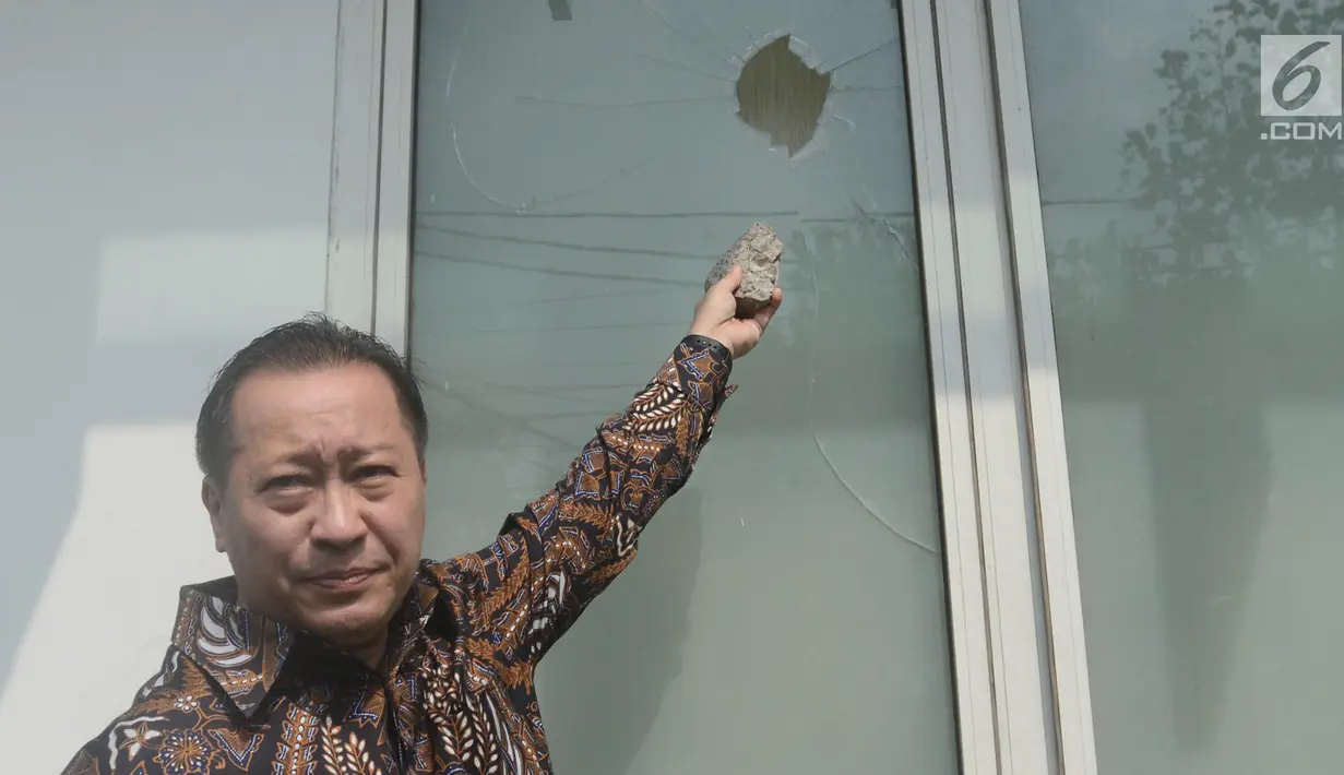 Wakil Ketua Umum PPP, Humphrey R Djemat menunjukkan kaca kantor DPP PPP di Jalan Diponegoro, Jakarta Pusat yang pecah akibat aksi penyerangan, Minggu (16/7). Kantor DPP PPP diserang puluhan orang tak dikenal dini hari tadi. (Liputan6.com/Herman Zakharia)