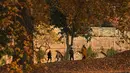 Sebuah keluarga Kashmir berjalan melewati pepohonan yang merontokkan daun musim gugur mereka di taman Nishat Bagh di Srinagar (16/11/2020). (AFP/Tauseef Mustafa)