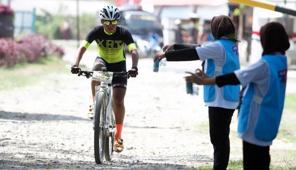 Petugas memberikan minuman kepada pebalap sepeda saat ambil bagian dalam kejuaraan Mountain Bike Cross Country Marathon (MTB XCM) di Kawasan Tanjung Lesung, Pandeglang, Banten, Sabtu (29/9). (Liputan6.com/HO/Nick)