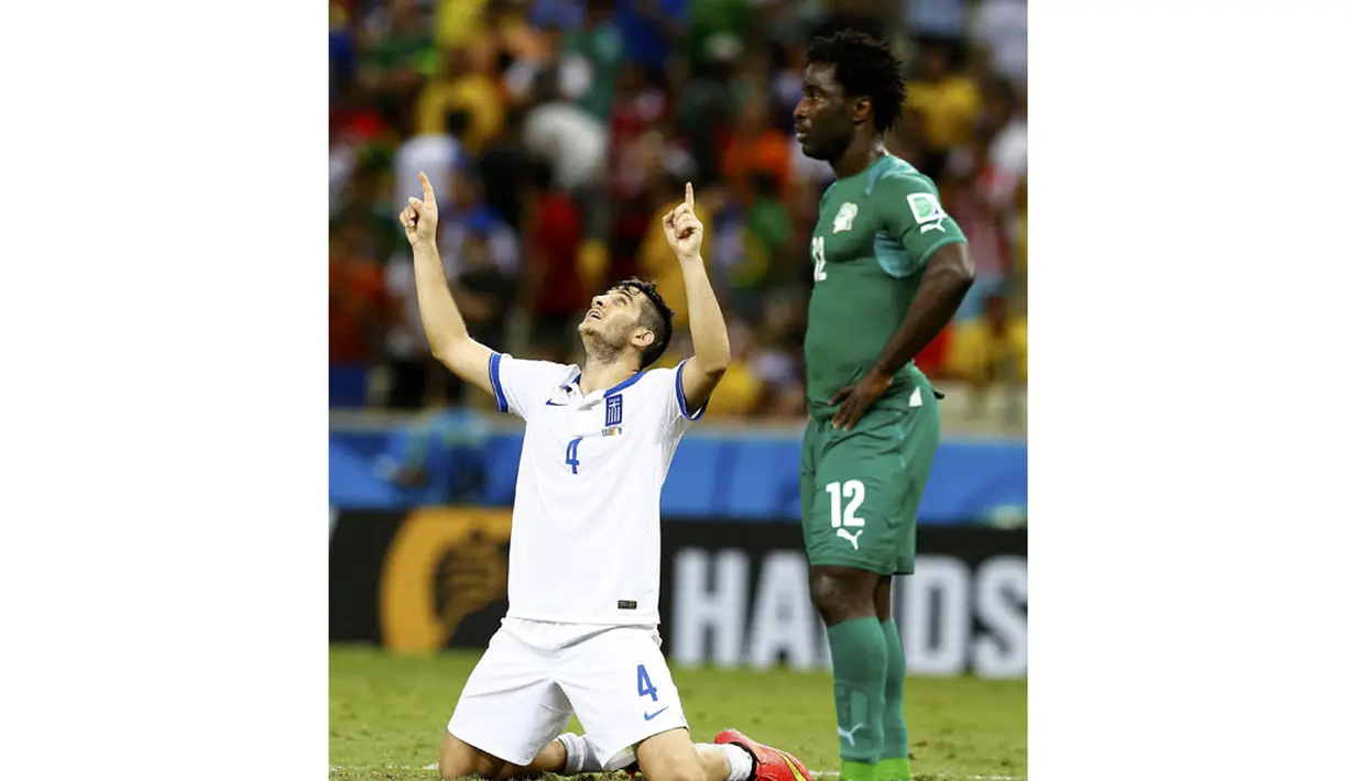 Pemain belakang Yunani, Kostas Manolas (kiri), menunjuk ke atas saat merayakan kemenangan atas Pantai Gading 2-1 di Stadion Castelao, Fortaleza, Brasil, (25/6/2014). (REUTERS/Marcelo Del Pozo)
