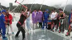 Seorang pria memukulkan palu untuk mencoba kekuatan kaca yang dipakai untuk jembatan di Provinsi Hunan, Cina, (25/6). Jembatan sepanjang 430 meter tersebut terbuat dari bahan kaca. (REUTERS / Jimmy Guan)