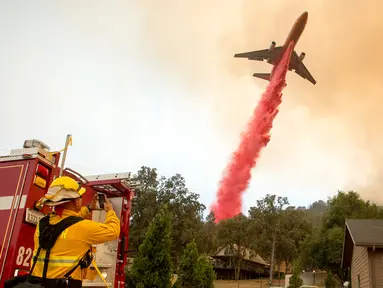 Pemadam kebakaran menggunakan pesawat membuang fire retardant untuk mengatasi kebakaran di Mariposa, California (19/7). Lebih dari 1.400 petugas pemadam kebakaran dikerahkan untuk menagatasi kebakaran tersebut. (AFP Photo/Josh Edelson)