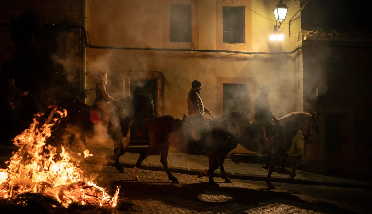 Orang-orang menunggangi kuda melewati api unggun selama festival Luminarias di San Bartolome de Pinares, Spanyol, Rabu (16/1). Festival yang digelar setiap tahunnya pada tanggal 16 Januari ini mulai dilaksanakan sekitar 500 tahun lalu. (AP/Felipe Dana)