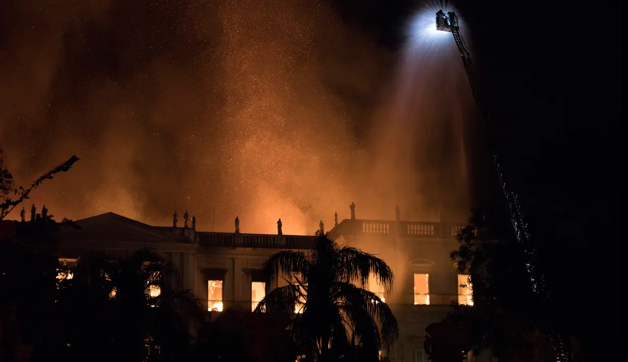 Petugas berusaha memadamkan api saat kebakaran Museum Nasional Brasil yang berusia 200 tahun di Rio de Janeiro, Minggu (2/9). Sejauh ini belum diketahui penyebab kebakaran bangunan bergaya kuno tersebut. (AP/Leo Correa)