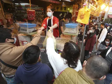 Warga mengenakan masker untuk mencegah penyebaran virus corona berbelanja untuk perayaan Tahun Baru Imlek di pasar Dihua Street di Taipei, Taiwan, Rabu (10/2/2021).  Warga Taiwan mulai berburu makanan lezat, barang kering, dan pernak-pernik lainnya untuk merayakan Imlek. (AP Photo/Chiang Ying-ying)