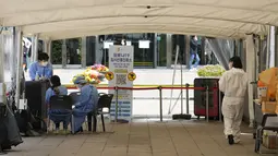 Pekerja medis menunggu orang-orang di pusat pengujian COVID-19 sementara di Seoul, Korea Selatan, Jumat (15/4/2022). Korea Selatan atau Korsel akan menghapus sebagain besar pembatasan covid-19 mulai pekan depan menyusul lonjakan kasus Omicron yang mulai berkurang. (AP Photo/Ahn Young-joon)