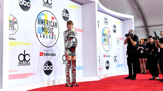 Penyanyi Taylor Swift menghadiri ajang American Music Awards 2018 di Los Angeles, Selasa (9/10). Taylor menyempurnakan penampilannya dengan boots sepaha, anting dan cincin dari Ofira Jewels serta Lorraine Schwartz. (Emma McIntyre/Getty Images/AFP)