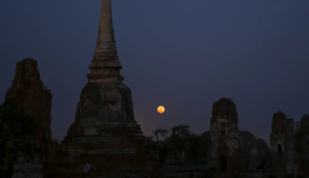 Bulan purnama terbit di belakang candi Wat Mahathat, Ayutthaya, Thailand (25/12/2015). Kerajaan Ayutthaya terkenal dengan harta karun yang berlimpah dan memiliki banyak arca dan patung-patung Buddha. (REUTERS/Jorge Silva)