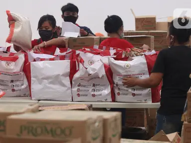 Pekerja sedang mengemas bantuan paket sembako dari Presiden Joko Widodo di Tangerang, Sabtu (9/6/2020).  Ribuan paket sembako tersebut akan didistribusikan kepada warga kurang mampu di wilayah Bodetabek guna mengurangi beban ekonomi mereka di tengah pandemi COVID-19. (Liputan6.com/Angga Yuniar)
