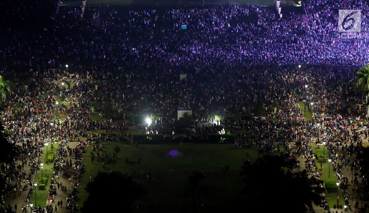 Ribuan warga memadati kawasan silang Monumen Nasional (Monas), pada malam pergantian tahun baru 2018 di Jakarta, Senin (1/1/2018). Monas menjadi salah satu lokasi pilihan warga saat malam tahun baru. (Liputan6.com/Johan Tallo)