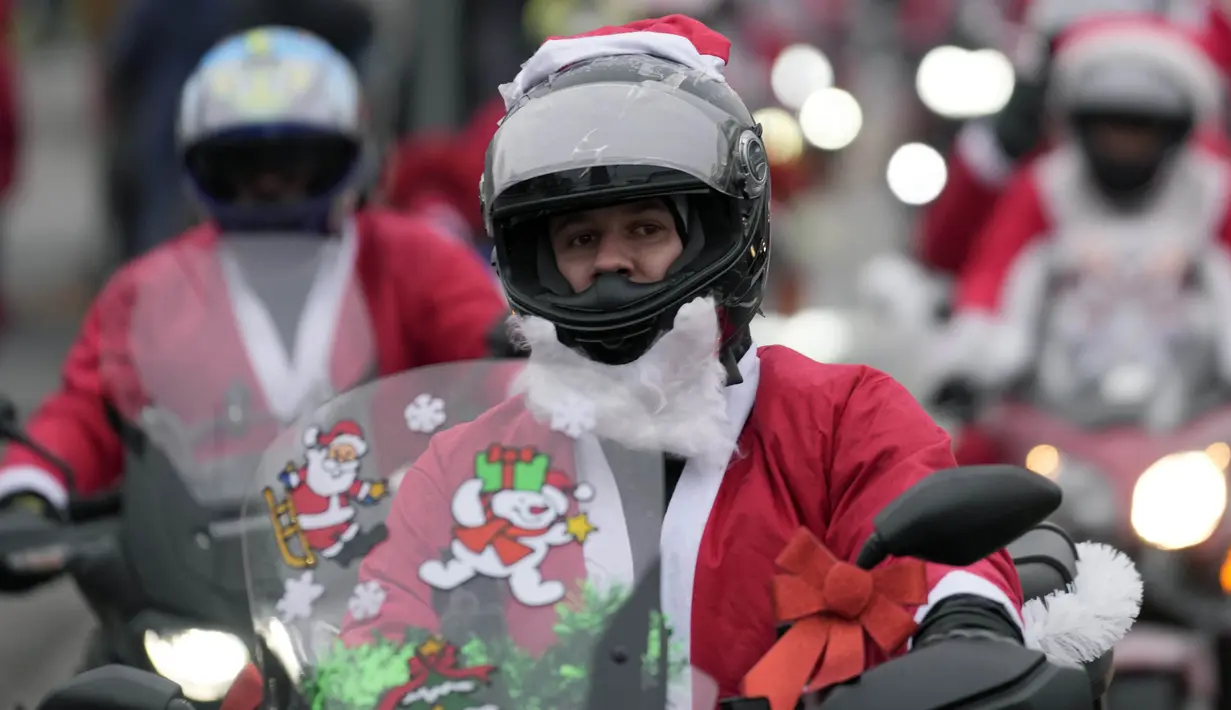 Seorang pengendara yang mengenakan kostum Sinterklas mengendarai motor selama parade Sinterklas di Beograd, Serbia, Minggu (26/12/2021). Mereka melakukan konvoi menuju rumah sakit anak-anak untuk membagikan mainan hadiah Natal kepada pasien di sana. (AP Photo/Darko Vojinovic)