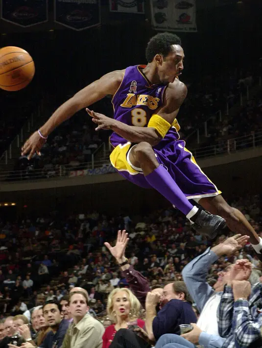 Pemain Los Angeles Lakers, Kobe Bryant melompati deretan penggemar setelah menyelamatkan bola saat bertanding melawan Houston Rockets di Houston pada 20 Desember 2001. Bryant memenangkan lima gelar juara NBA dan peraih medali emas Olimpiade dua kali. (AP Photo/Pat Sullivan)