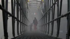 Seorang wanita Nepal menyusuri jembatan bersama anaknya untuk mengikuti festival Gaya Aunsi di Kathmandu, Nepal (21/12). Ritual suci ini digelar untuk memberi doa dan penghormatan kepada anggota keluarga yang telah meninggal. (AP Photo/Niranjan Shrestha)