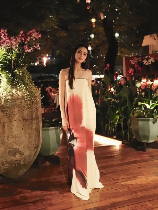 Saat malam tiba, Alyssa memilih tampilan lain yang tak kalah memikat. Ia mengenakan strapless dress putih dengan motif bunga  yang memancarkan aura chic dan sophisticated. Dress ini semakin serasi dengan gemerlap lampu kota Bangkok dan kembang api yang menjadi latar romantis malam mereka. [@alghazali7].