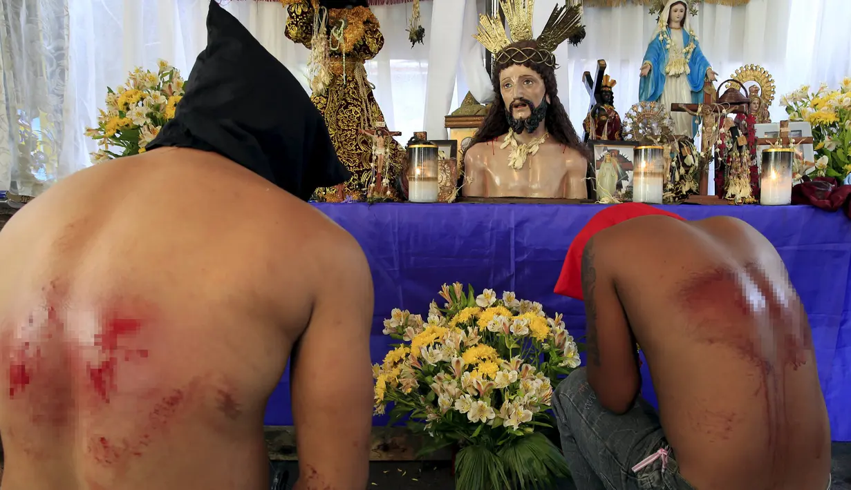 Pria berdoa dengan memakai topeng pada acara kamis putih di kota Mandaluyong, Manila, Filipina, (24/3). Tradisi cambuk merupakan tradisi yang dilakukan oleh beberapa umat Katolik Filipina untuk menyambut hari Paskah. (REUTERS / Romeo Ranoco)