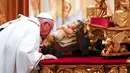 Paus Fransiskus mencium patung bayi Yesus saat memimpin misa Natal di Basilika Santo Petrus, Vatikan, (24/12).  Pada misa tersebut, Paus mengatakan bahwa Natal sudah "disandera" oleh materialisme. (REUTERS/Tony Gentile)