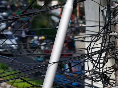 Kabel listrik dan kabel optik yang terlihat semrawut di kawasan Taman Puring, Jakarta, Jumat (3/7/2020). Kesemrawutan kabel ini sering terlihat di sejumlah kawasan Jakarta yang menyebabkan keindahan menjadi hilang dan pemandangan kurang enak untuk dilihat. (Liputan6.com/Johan Tallo)