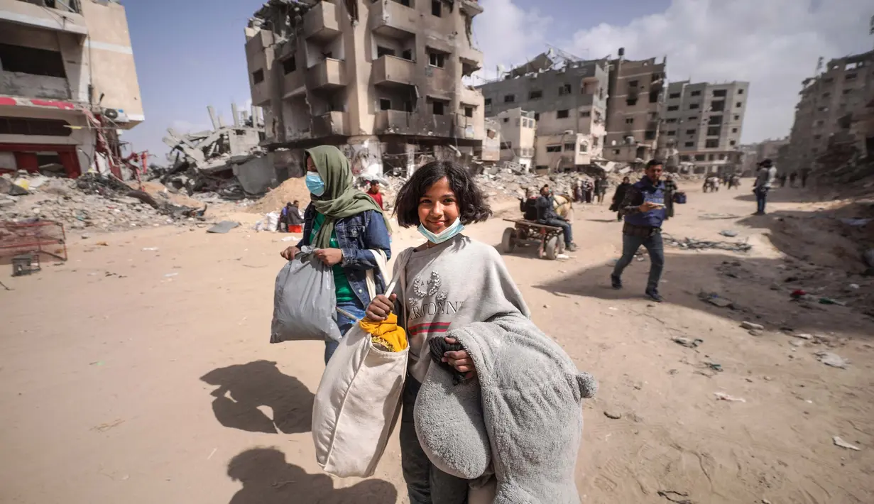 Warga Palestina mengungsi melalui jalan di dekat reruntuhan rumah yang hancur di Khan Yunis, Jalur Gaza selatan pada 6 Maret 2024. Kementerian Kesehatan Gaza mendesak institusi internasional untuk mendukung keperluan hidup, kesehatan, psikologis, dan sosial perempuan Palestina, terutama di Jalur Gaza. (Foto oleh AFP)