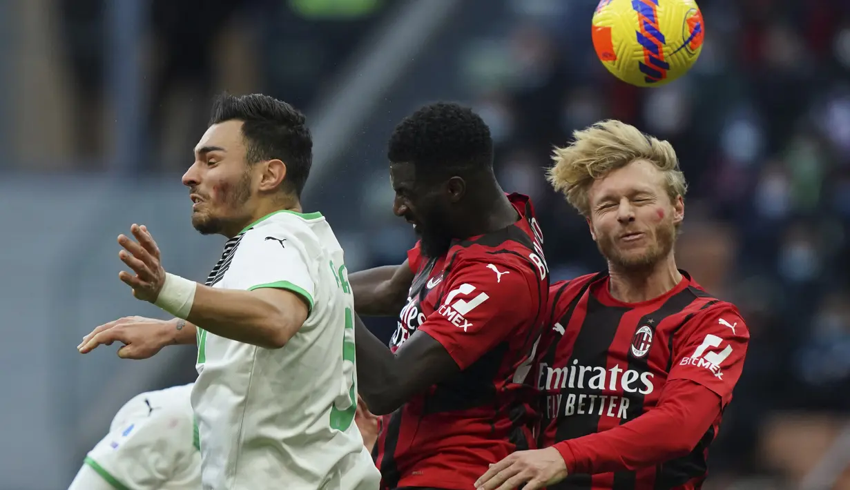 Bek AC Milan, Simon Kjaer dan gelandang Tiemoue Bakayoko berebut bola udara dengan pemain Sassuolo, Kaan Ayhan pada pertandingan lanjutan Liga Serie A Italia di stadion San Siro, Minggu (28/11/2021). AC Milan kalah atas Sassuolo 1-3. (Spada/LaPresse via AP)