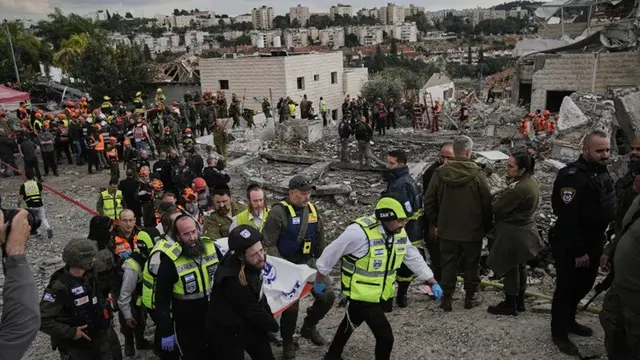 Petugas penyelamat dan personel militer mengangkat jenazah korban di lokasi serangan rudal Iran di Beit Shemesh, Israel, Minggu (1/3/2026), setelah beberapa orang tewas akibat serangan tersebut.