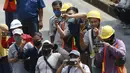 Para pekerja proyek mengabadikan momen parade pembalap MotoGP di depan Sarinah Thamrin, Jakarta Pusat. Sebanyak 20 pembalap melakukan parade motor dari Istana Merdeka menuju Hotel Kempinski di Bundaran HI Jakarta Pusat, Rabu (16/03/2022). (Bola.com/M Iqbal Ichsan)