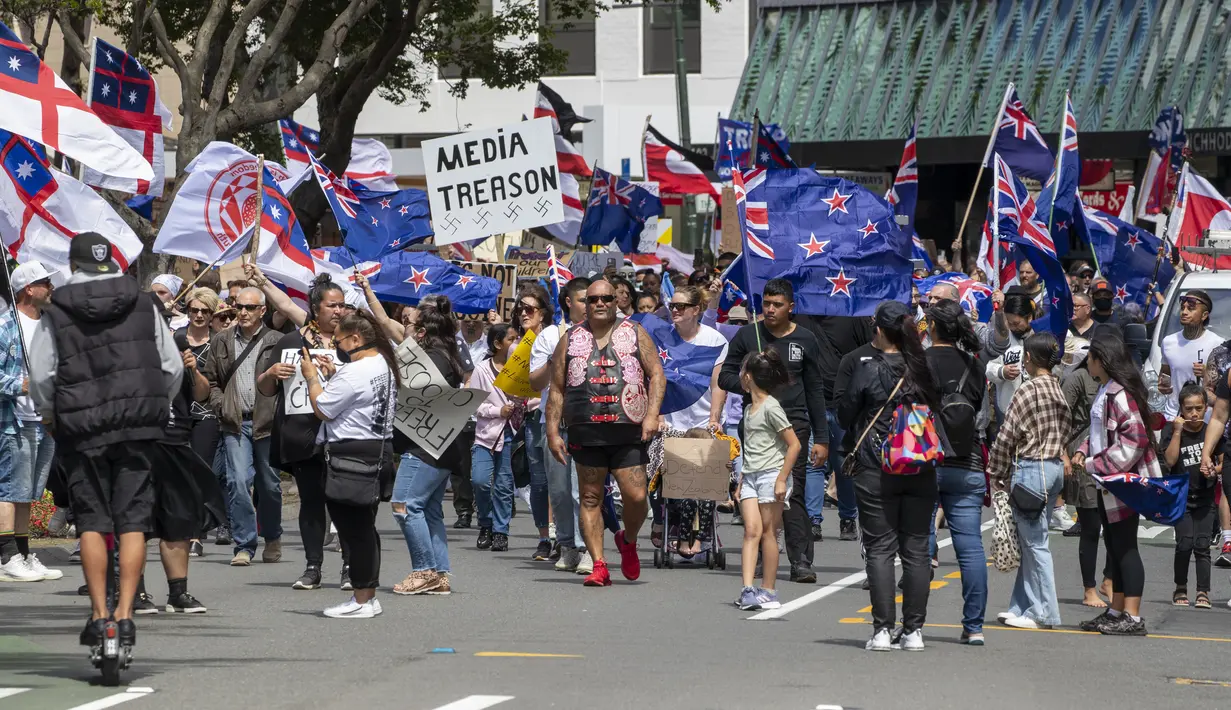 Demonstran berbaris di sepanjang Lambton Quay sebelum berkumpul di gedung Parlemen Selandia Baru, di Wellington, Selasa (9/11/2021). Ribuan warga Selandia Baru berdemonstrasi memprotes kebijakan vaksin covid-19 dan penguncian (lockdown) yang diterapkan negara itu. (Mark Mitchell/NZ Herald via AP)