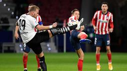 Gelandang Valencia, Uros Racic (kiri) bersaing dengan gelandang Atletico Madrid, Marcos Llorente pada jornada ke-20 Liga Spanyol di Wanda Metropolitano, Senin (25/1/2021) dini hari WIB. Atletico Madrid memetik kemenangan 3-1 atas Valencia. (PIERRE-PHILIPPE MARCOU/AFP)
