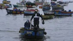 Seorang nelayan memegang ikan yang ditangkapnya di perairan yang terkontaminasi tumpahan minyak, di Ancon, Peru, Kamis (20/1/2022). Tumpahan minyak di pantai Peru disebabkan oleh gelombang dari letusan gunung berapi bawah laut di negara Pasifik Selatan Tonga. (AP Photo/Martin Mejia)