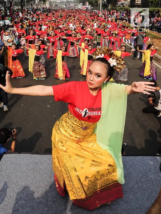 Seorang penari diikuti ribuan peserta membawakan Tari Puspanjali dari Bali saat CFD di Senayan, Jakarta, Minggu (12/8). Kegiatan ini digelar menyambut HUT Ke-73 RI dan Asian Games 2018. (Liputan6.com/Fery Pradolo)