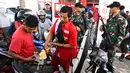 Tentara berjaga saat korban gempa dan tsunami mengantre untuk mendapatkan bahan bakar minyak (BBM) di SPBU Kota Palu, Sulawesi Tengah, Senin (1/10). Pengawalan oleh tentara bersenjata untuk menghindari penjarahan oleh warga. (Jewel Samad/AFP)