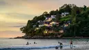 Orang-orang berselancar di pantai, saat para turis memanfaatkan program "Kotak Pasir Phuket" untuk pengunjung yang telah divaksinasi penuh terhadap virus corona Covid-19 di pulau Phuket Thailand (25/10/2021). (AFP/Mladen Antonov)