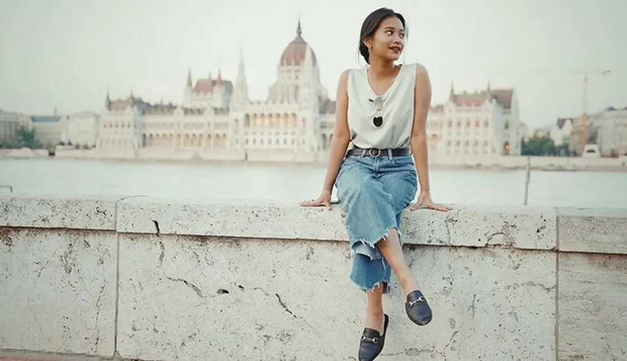 Di saat ingin tampil dengan denim, paduan blouse tanpa lengan bernuansa putih menjadi gaya yang nyaman digunakan kala berlibur. (Foto: Instagram/ Siti Adira Kirana)
