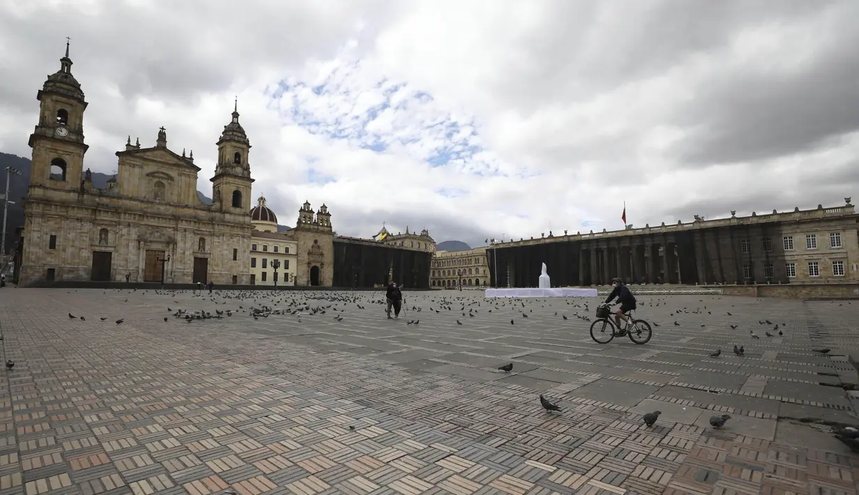 Seorang pria mengendarai sepedanya melalui Bolivar Square yang biasanya ramai di tengah lockdown yang diberlakukan kembali di Bogota, Sabtu (10/4/2021). Kota-kota besar Kolombia memulai akhir pekan pertama lockdown ketat untuk mengurangi penyebaran gelombang ketiga corona (AP Photo/Fernando Vergara)