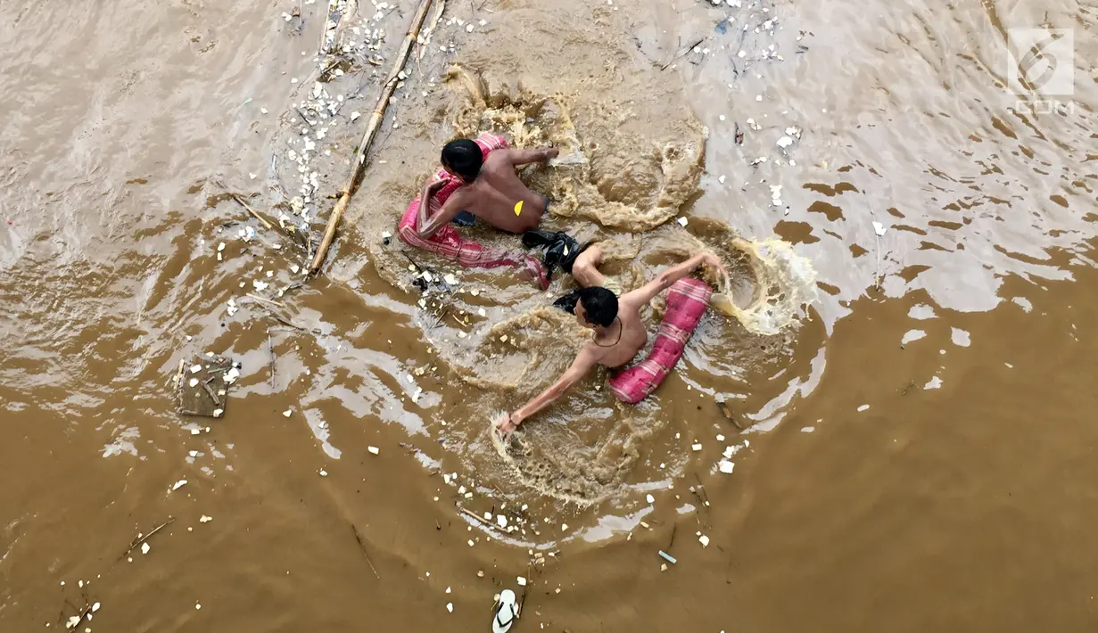 Suasana saat warga berenang di derasnya arus Sungai Ciliwung, Rawajati, Jakarta, Selasa (6/2). Warga tidak memperhatikan bahaya yang mengancam nyawa mereka. (Liputan6.com/Immanuel Antonius)