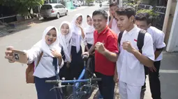 Legenda tinju Indonesia, Ellyas Pical, foto bersama pelajar di Kawasan Bintaro, Jumat (13/7/2018). Ellyas Pical adalah petinju Indonesia pertama yang berhasil menjadi juara dunia. (Bola.com/M Iqbal Ichsan)