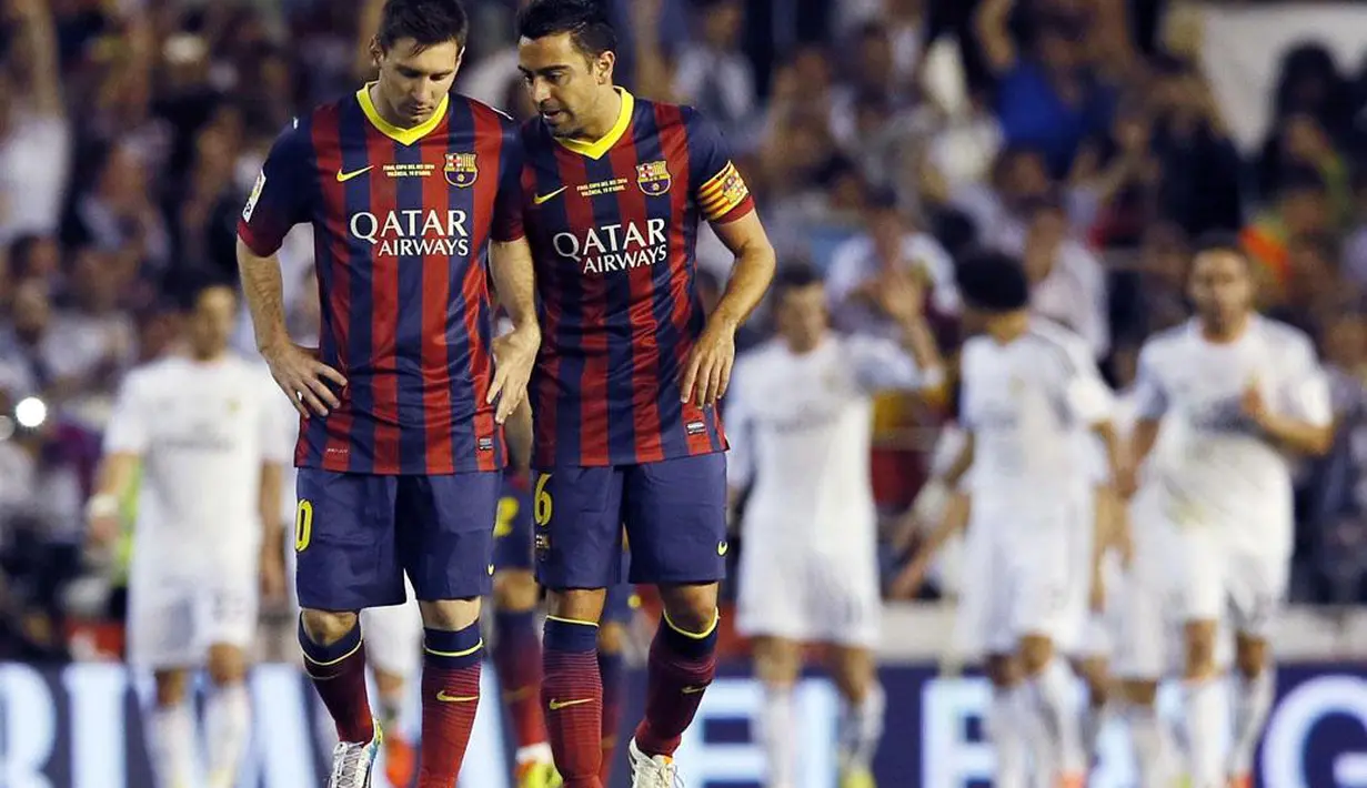 Kapten tim Barcelona, Xavi Hernandez (kanan) berjalan tertunduk bersama Lionel Messi usai dikalahkan Real Madrid 1-2 di pada final Piala Raja di Stadion Mestalla, Valencia (17/4/2014). (REUTERS/Albert Gea)