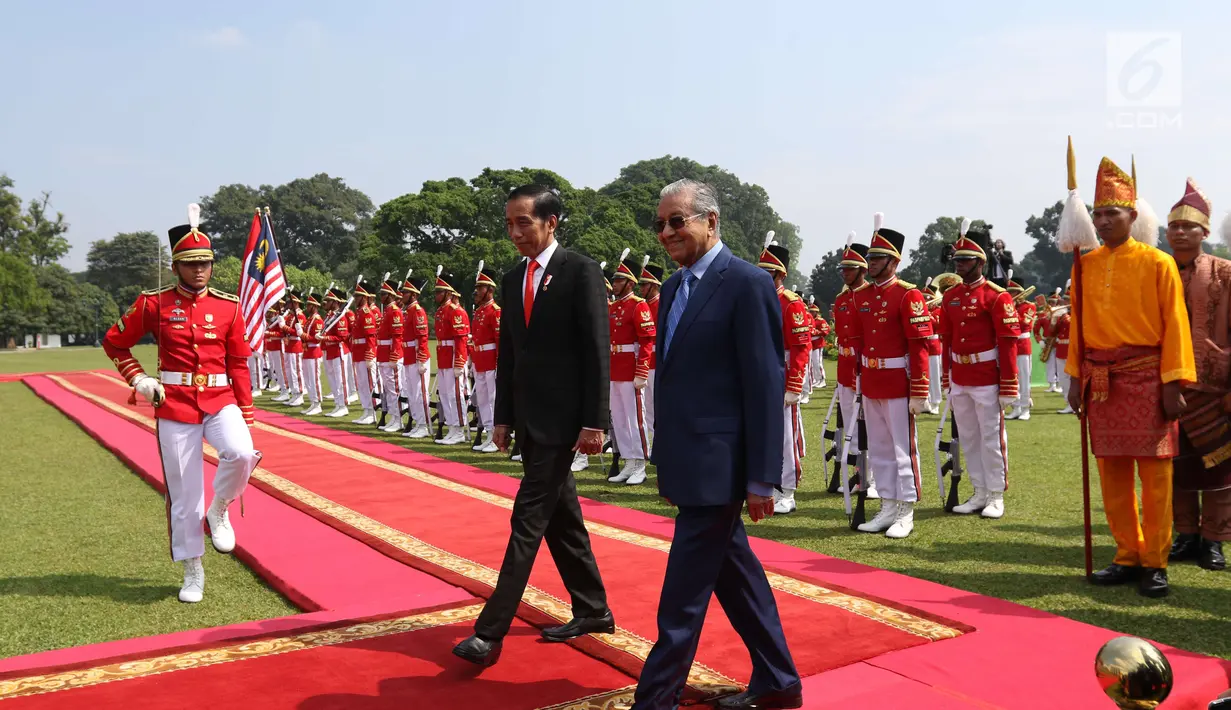Presiden Joko Widodo dan PM Malaysia, Mahathir Mohamad memasuki Istana Bogor seusai upacara penyambutan tamu negara, Jumat (29/6). Indonesia menjadi negara pertama yang dikunjungi secara resmi oleh PM Mahathir usai dilantik. (Liputan6.com/Angga Yuniar)