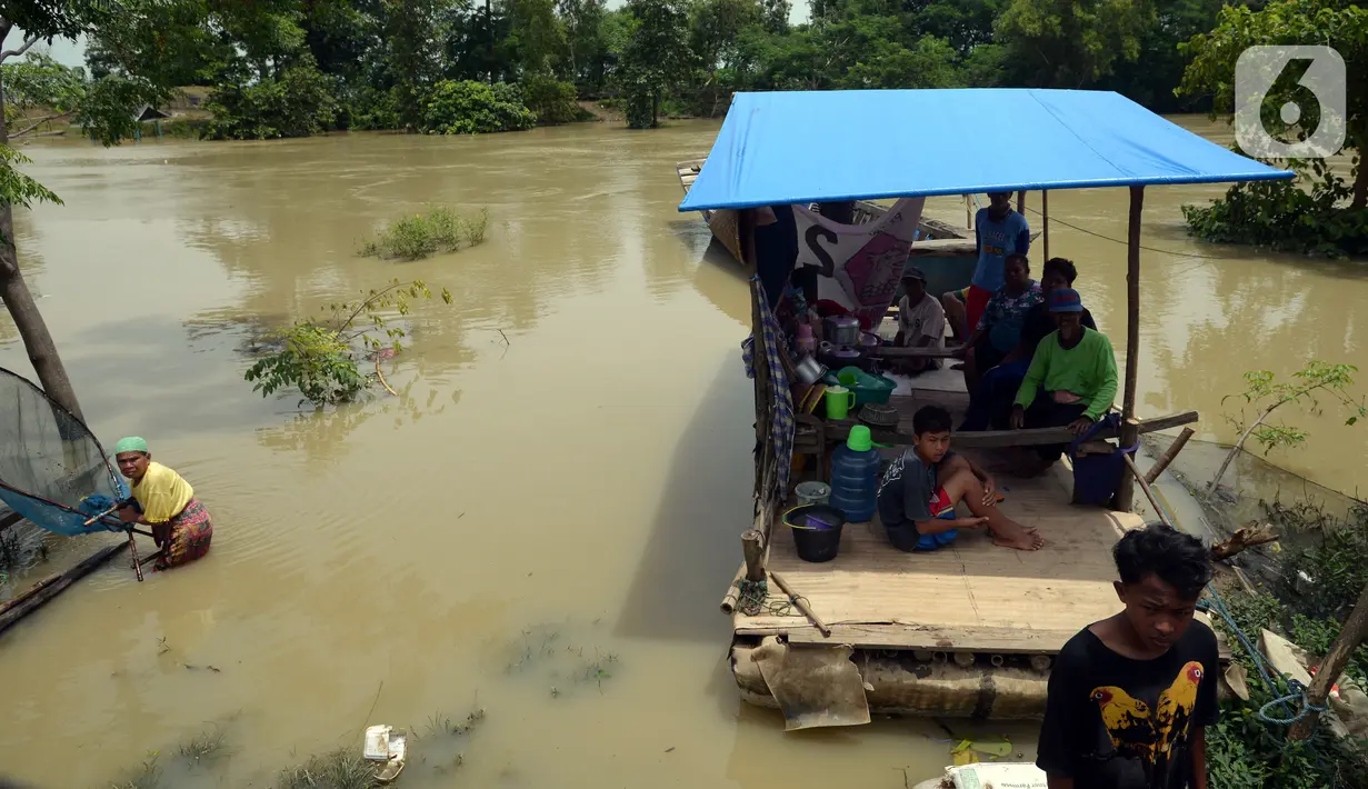 Warga menaiki perahu saat melintasi banjir di Desa Sindangsari, Kabupaten Bekasi, Jawa Barat, Rabu (24/2/2021). Sebagian rumah warga masih terendam banjir yang disebabkan jebolnya tanggul Sungai Citarum dan luapan Sungai Ciherang. (merdeka.com/Imam Buhori)