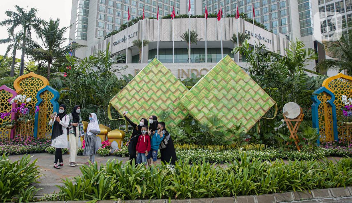 <p>Sejumlah warga berfoto dengan dekorasi bertemakan Idul Fitri di kawasan Bundaran HI, Jakarta, Rabu (27/4/2022). Dekorasi berbentuk masjid, ketupat, dan bedug yang dihiasi oleh tanaman tersebut dalam rangka menyambut Idul Fitri 1443 Hijriah. (Liputan6.com/Faizal Fanani)</p>