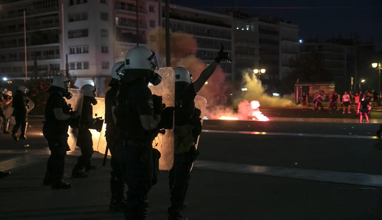 Polisi Yunani mengamankan area ketika pengunjuk rasa antivaksin melemparkan suar dan bom molotov selama rapat umum di alun-alun Syntagma, Athena tengah (24/7/2021). Aksi protes berlangsung ricuh usai beberapa pedemo melemparkan bom molotov ke arah polisi. (AP Photo/Yorgos Karahalis)