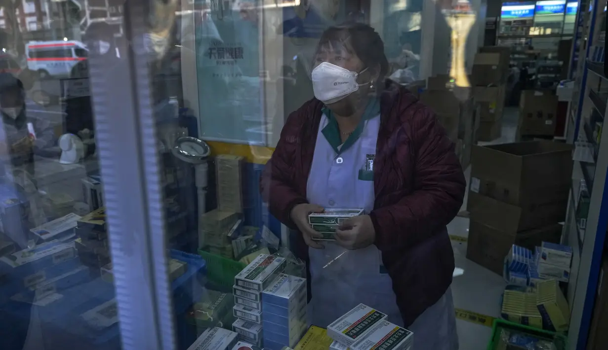 Warga tercermin di panel pintu saat mengantre untuk membeli obat di apotek di Beijing, Selasa (13/12/2022). Beberapa universitas di China mengatakan akan mengizinkan mahasiswanya menyelesaikan semester dari rumah dengan harapan mengurangi potensi wabah COVID-19 yang lebih besar selama kesibukan perjalanan Tahun Baru Imlek di bulan Januari mendatang. (AP Photo/Andy Wong)