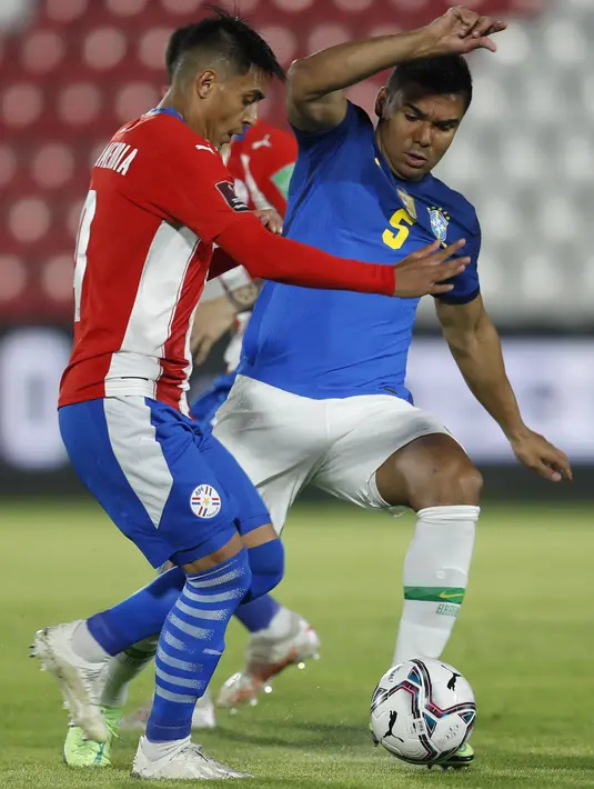 Gelandang timnas Brasil, Casemiro dan bek Paraguay, Santiago Arzamendia berebut bola dalam lanjutan Kualifikasi Piala Dunia 2022 zona Amerika Selatan di stadion Defensores del Chaco, Kamis (9/6/2021) pagi WIB. Brasil meraih kemenangan dengan skor 2-0. (AP Photo/Jorge Saenz)