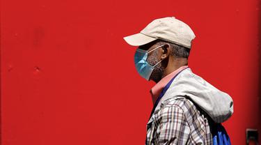 Seorang pejalan kaki yang mengenakan masker berjalan di Philadelphia, Jumat (22/4/2022). Kota itu meninggalkan mandat masker dalam ruangan pada hari Jumat, hanya beberapa hari setelah menjadi kota metropolitan AS pertama yang menerapkan kembali wajib masker sebagai tanggapan atas peningkatan kasus COVID-19 dan rawat inap. (AP Photo/Matt Rourke)