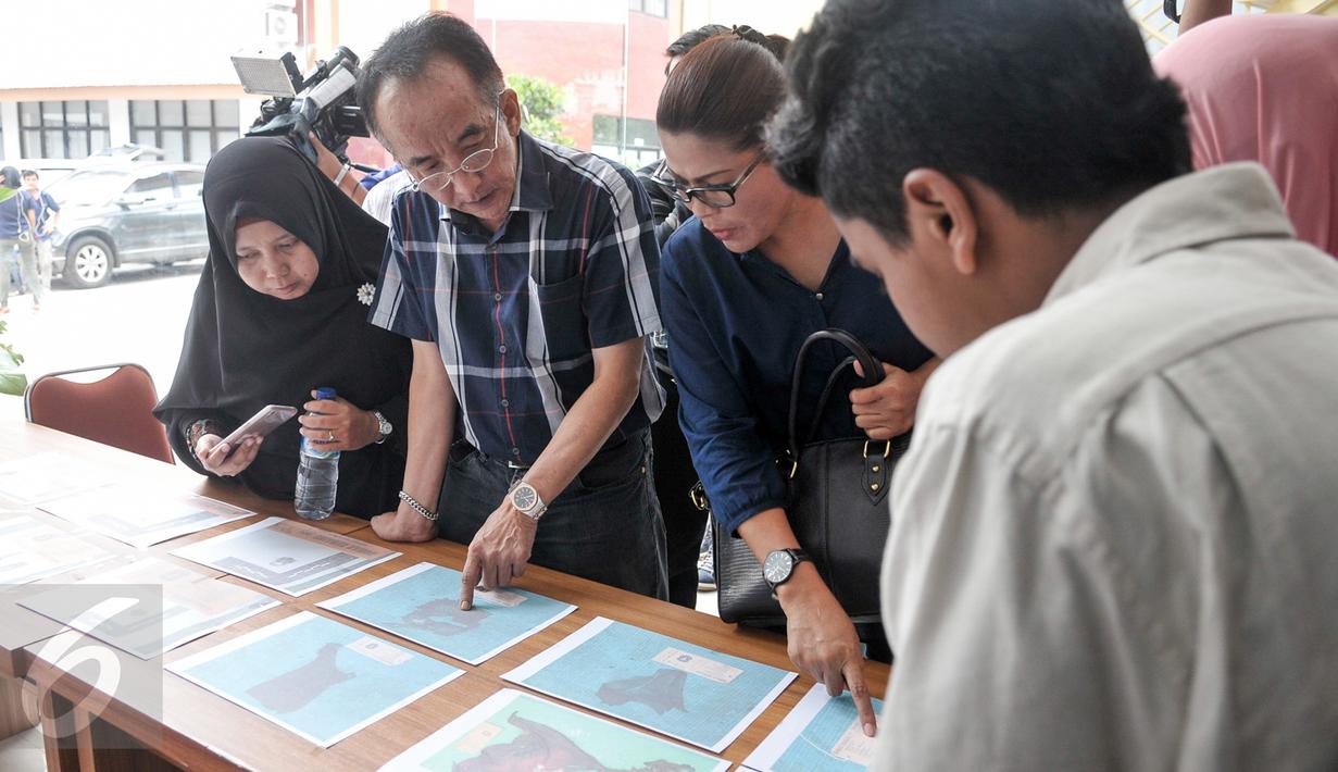 Keluarga korban melihat foto properti dari jenazah korban KM Zahro yang belum teridenfikasi di RS Polri, Jakarta, Selasa (3/1). Penempelan foto hasil postmortem bertujuan untuk membantu pengenalan oleh pihak keluarga. (Liputan6.com/Yoppy Renato)