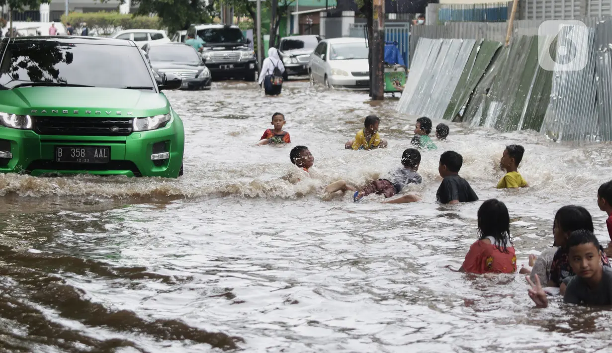 Anak anak bermain air di sebagian Jalan Bungur Besar Raya yang tergenang, Jakarta, Selasa (18/1/2022). Genangan air di sebagian Jalan Bungur Besar Raya dimanfaatkan anak-anak untuk bermain meski berbahaya. (Liputan6.com/Helmi Fithriansyah)