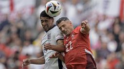 Pemain Inggris, Jude Bellingham berduel udara dengan pemain Swiss, Fabian Schaer saat laga perempat final Euro 2024 di Duesseldorf Arena, Duesseldorf, Jerman, Sabtu (06/07/2024). (AP Photo/Thanassis Stavrakis)